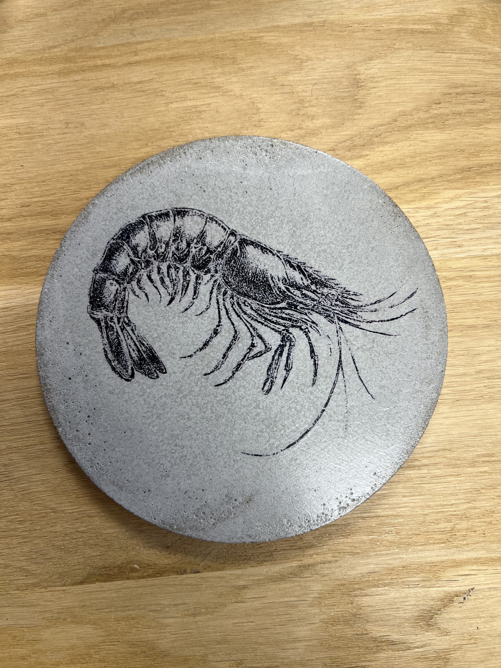 Apportez une touche d’originalité à votre table avec le sous-plat crevette, une création en béton au design marin et graphique. Fabriqué en France.